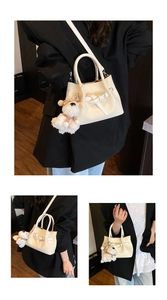 Détail d'un sac seau blanc crème avec charm chiot en peluche et bandoulière en cuir souple