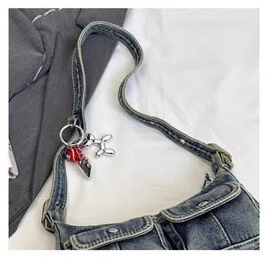 Close-up of blue denim baguette bag featuring utility pockets and y2k metal charms