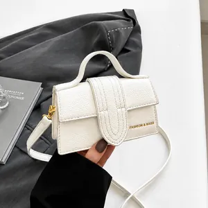Close-up of white lychee-patterned handbag with gold FASHION & BAGS lettering and hardware