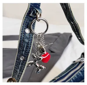 Detail of silver balloon dog bag charm with red pompom on a blue denim baguette bag