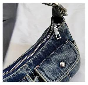 Detail view of smooth silver zipper and rugged washed denim texture on shoulder bag
