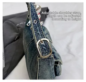 Detail of adjustable denim shoulder strap with silver buckles and eyelets on blue bag