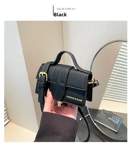 Detail of black pebbled leather square bag with gold buckle and fashion text logo