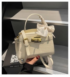Détail du sac à main blanc motif crocodile avec fermoir doré et nœud en satin