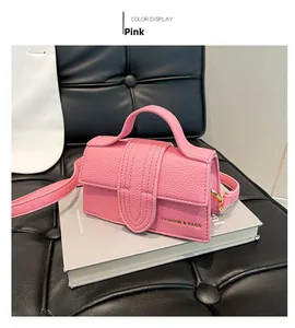 Pink minimalist crossbody bag with textured faux leather and adjustable strap on a book