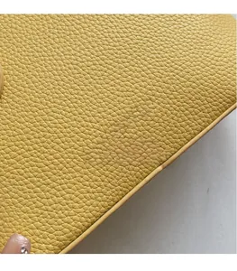Macro detail of yellow lychee texture leather with silver Chris'2ab brand logo