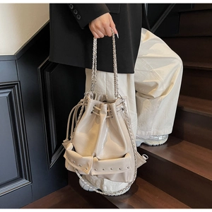 Detail of cream stud bucket bag with silver chain straps shown on a model