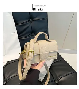 Detail of khaki mini handbag with lychee texture and adjustable strap held by hand