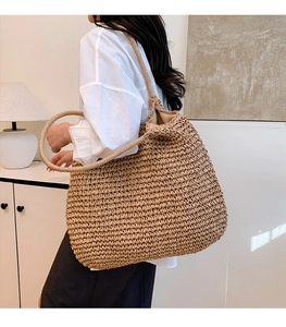 Detail of straw tote bag showing hand-woven texture and circular handle on model