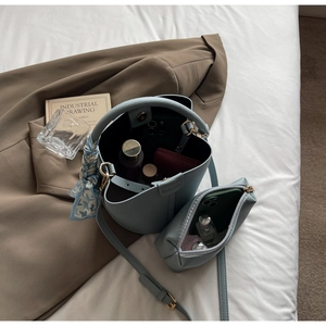 Détail du sac seau bleu clair à texture litchi avec pochette assortie et foulard en soie