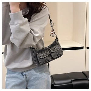 Detail of black denim crossbody bag with silver hardware and a metallic dog charm