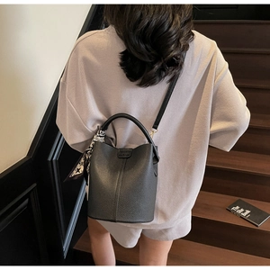Détail d'un sac seau en cuir grainé noir avec un foulard décoratif en soie élégant