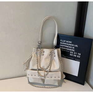 Detail of cream white bucket bag featuring silver rivet studs and polished metal chains