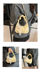 Detail of light yellow ruched handbag with white lace bow and faux pearl chain