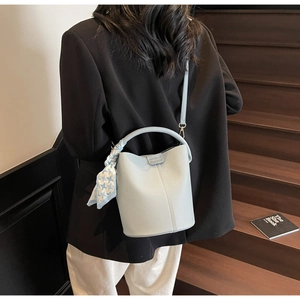 Gros plan sur sac seau bleu clair motif litchi avec foulard en soie à carreaux décoratif