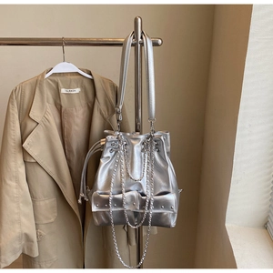 Silver metallic bucket bag detail with drawstring closure and rivet pocket accents
