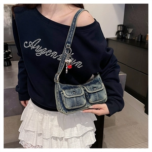 Detail of vintage denim shoulder bag with heart pendant and adjustable metal eyelet strap