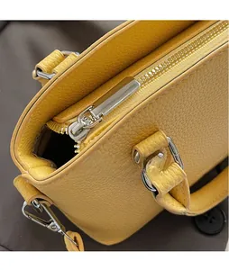 Detail of silver zipper and D-ring on yellow lychee texture leather handbag