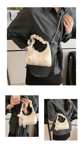 Detail of cream pleated cloud bag with lace bow, pearl charm and metal chain strap