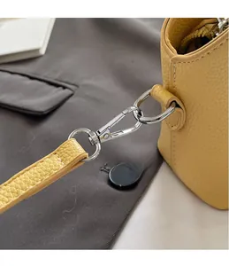 Macro shot of silver metal hook and D-ring on yellow lychee grain leather handbag