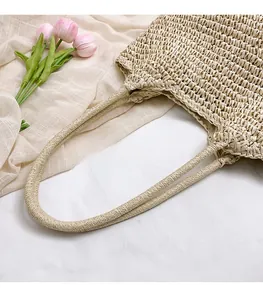 Detail of sturdy beige woven straw handles with intricate hollow texture on a summer tote
