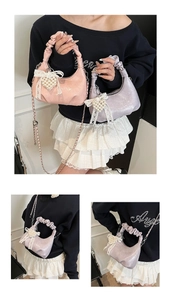 Detailed macro of shiny pleated faux leather handbag with pearl heart charm accessory