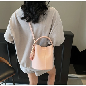 Gros plan du sac seau en cuir rose avec gaufrage de mode et détail d'écharpe en soie chic