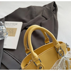 Detail of yellow lychee pattern bucket bag with pearl lace bow and silver hardware
