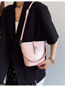 Sac seau rose texture crocodile avec fermoir argenté porté avec un blazer noir chic