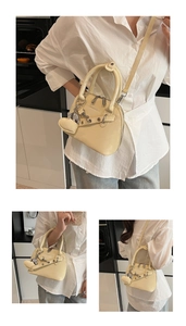 Détail du sac à main beige en forme de coquillage avec chaîne coeur et bandoulière