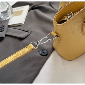 Detail of yellow lychee texture leather bucket bag with silver metal D-ring and strap