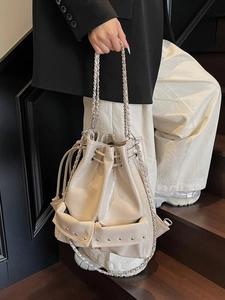 Chic beige bucket bag with silver studs and chain strap in glossy faux leather finish
