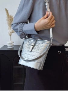 Sac seau argenté à motif crocodile avec bandoulière porté par un mannequin