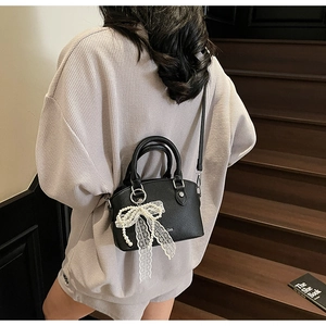Litchi pattern black bucket bag with a pearl lace bow charm shown on a model