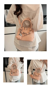 Détail du sac coquille en cuir verni rose avec breloque cœur et chaîne argentée