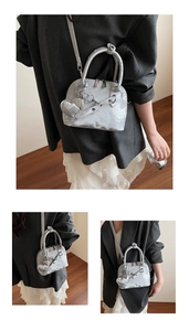 Détails du sac bandoulière métallisé en forme de coquille avec texture et pendentif cœur