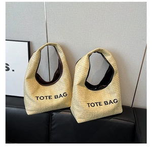 Detailed macro view of straw woven tote bag with contrast TOTE BAG lettering and texture