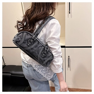 Detail of dark grey washed denim Y2K shoulder bag with white stitching and silver rivets