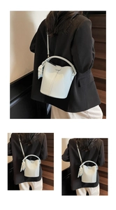 Détail du sac seau bleu clair en cuir avec foulard géométrique sur escalier en bois