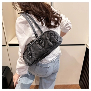 Washed denim Boston bag shown on shoulder, featuring Y2K style with metal rivets