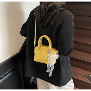 Detail of yellow lychee texture bucket bag with pearl lace bow charm on model