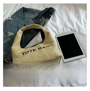 Detailed view of woven raffia tote bag with TOTE BAG print on casual background