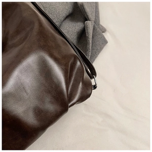 Vue rapprochée du cuir souple marron foncé vintage et de la finition brillante du sac