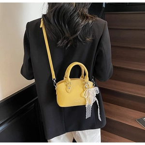 Detail of yellow lychee leather bucket bag with lace pearl charm and adjustable strap