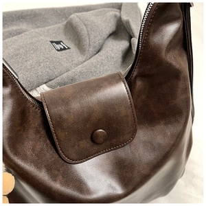 Détail d'un sac bandoulière rétro en cuir marron foncé avec fermeture éclair métallique