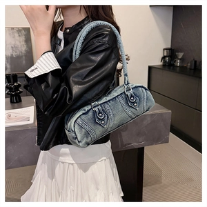 Detailed close-up of a blue washed denim Boston bag featuring stylish metal buckles