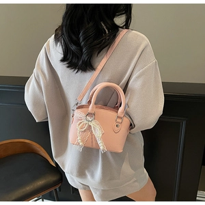 Pink bucket bag in lychee pattern leather with pearl lace bow charm on model back