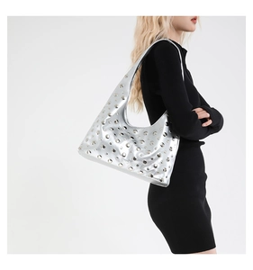 Silver crescent hobo bag with metallic studs worn by a model in a side view