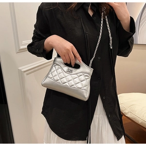 Détail du sac matelassé argenté avec finition métallique et fermoir rotatif en métal