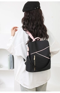 Rear view of fashion backpack with black nylon and pink trim worn by a model